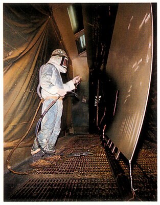 Person in protective suit sprays ec-3960 onto fuselage skin to prevent against corrosive environments